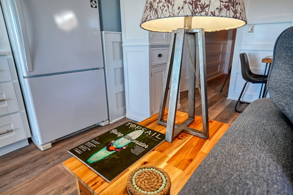 This image showcases a cozy interior living area with a lampshade softly illuminating a coffee table, a magazine, and a textured rug. The overall mood is comfortable and relaxed, evoking feelings of unwinding after a day spent exploring the island.